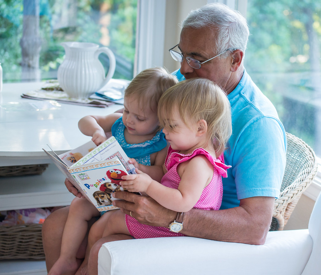 Three generations at home — a grandparent reading with two small children